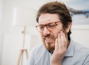 Teeth problem, guy suffering from tooth pain and caries
